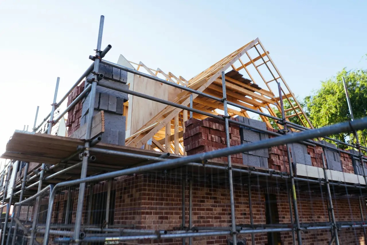 Chantier de maison en cours : échafaudage, charpente et briques