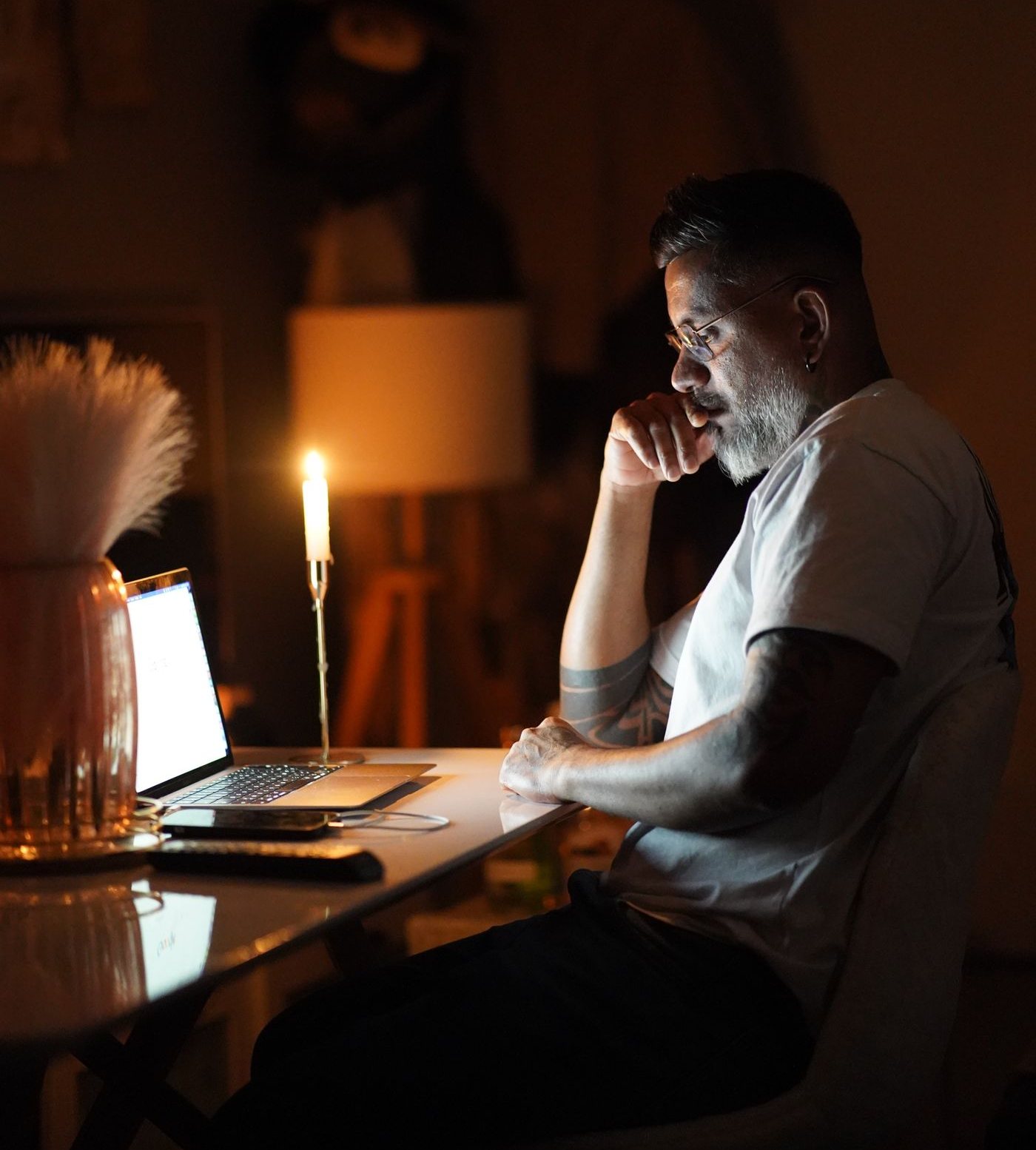 Un artisan devant son ordinateur portable, le soir, à la lueur d'une bougie